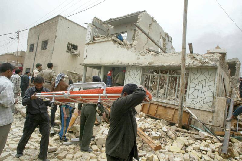 Rescuers carry a stretcher over the debris of a house destroyed in a US bombing of Baghdad's al-Aazamiya neighborhood 24 March 2003. Five members of the same family were killed and at least 28 others wounded when a missile fired by allied warplanes hit houses in the densely populated area in the Iraqi capital, according to residents. AFP PHOTO/Ramzi HAIDAR (Photo by RAMZI HAIDAR / AFP)