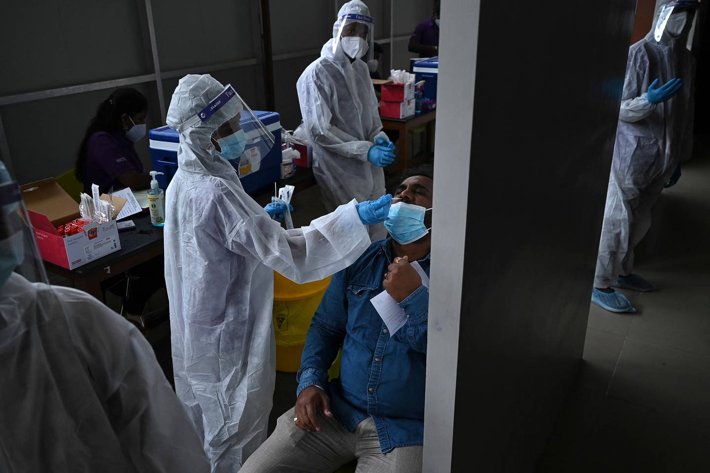 A health worker collects a swab sample from a passenger arriving at Anna International Airport in Chennai. AFP