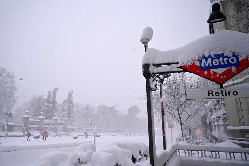 People walk past the Retiro subway station as heavy snowfall continues in Madrid. AFP