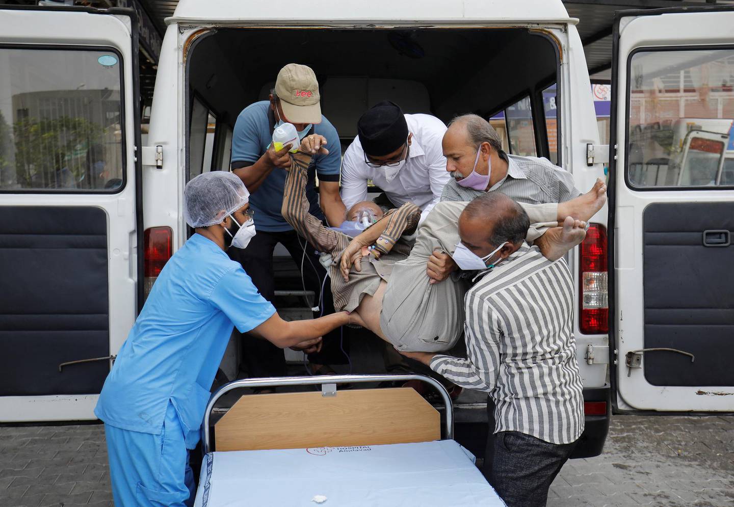 Healthcare workers and relatives carry Shashikantbhai Parekh, a patient with breathing problem, out from an ambulance for treatment at a COVID-19 hospital, amidst the spread of the coronavirus disease (COVID-19) in Ahmedabad, India, April 28, 2021. REUTERS/Amit Dave