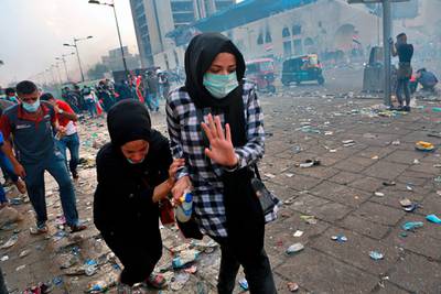 Iraqi women run to take cover while security forces fire tear gas during anti-government protests in Tahrir Square in Baghdad, Iraq.  AP Photo