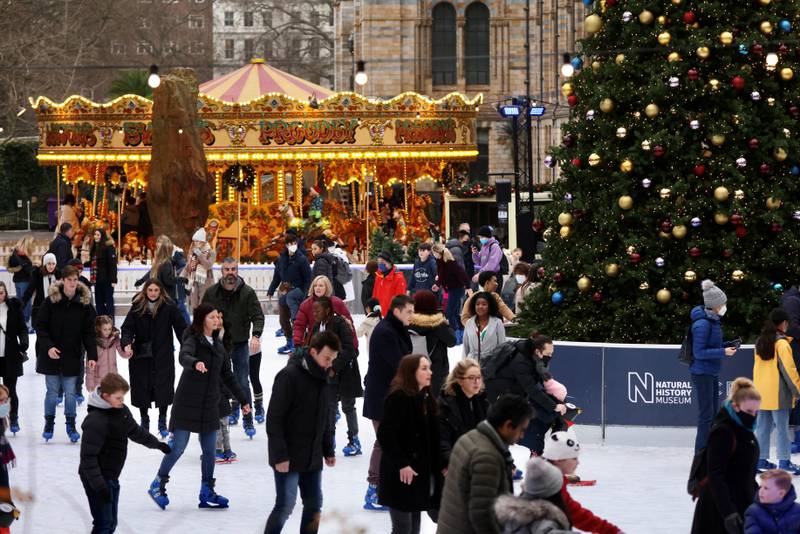 People, most of them without masks, skate around the Christmas tree at the Natural History Museum in London. Reuters