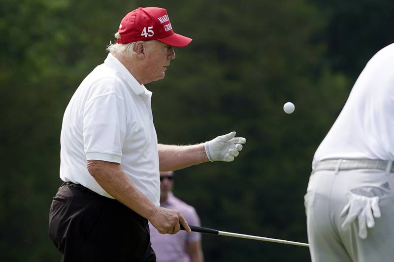 Mr Trump tosses a ball after playing the second hole. AP