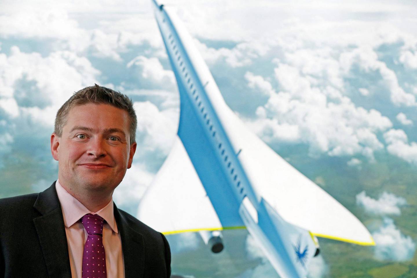 (FILES) In this file photo taken on July 18, 2018, Boom Supersonic co-founder, Blake Scholl, poses for a photograph in front of an artists impression of his company's proposed design for an supersonic aircraft, dubbed Baby Boom, at the Farnborough Airshow, southwest of London.  United Airlines announced plans on June 3, 2021, to buy 15 planes from airline startup Boom Supersonic in a move that could revive the high-speed form of air travel. Under the commercial agreement, United would purchase Boom's "Overture" aircraft once the planes meet "United's demanding safety, operating and sustainability requirements" with an aim to start passenger travel in 2029, the companies said in a joint press release.
 / AFP / Adrian DENNIS
