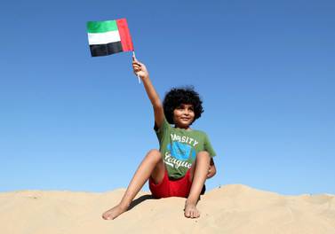 Hussein, 8, waves his flag in the desert on National Day. Chris Whiteoak / The National