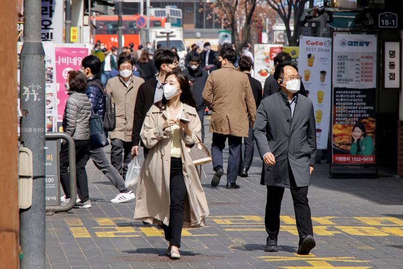 People wearing masks walk in Seoul, South Korea, on March 16. Reuters