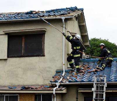 Firefighters try to remove debris on the damaged roof of a house, after a magnitude 6.1 earthquake in Osaka. EPA