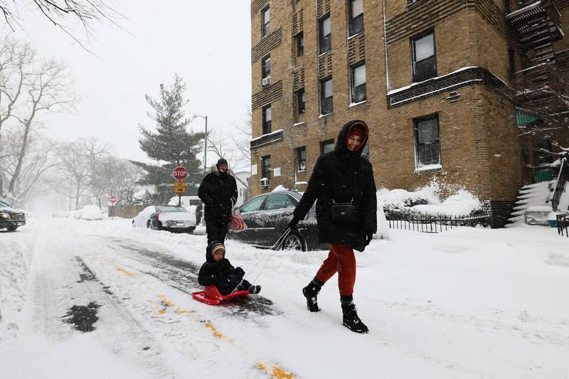 A child is pulled on a sled along 14th Street in the Midwood neighborhood of Brooklyn. NYC Mayor Bill de Blasio declared a State of Emergency and MTA officials announced that above-ground subway service would be suspended. AFP