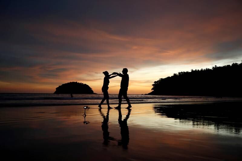 Local residents Stavros from Greece and Valina from Russia dance on an almost empty Kata beach in Phuket. Reuters