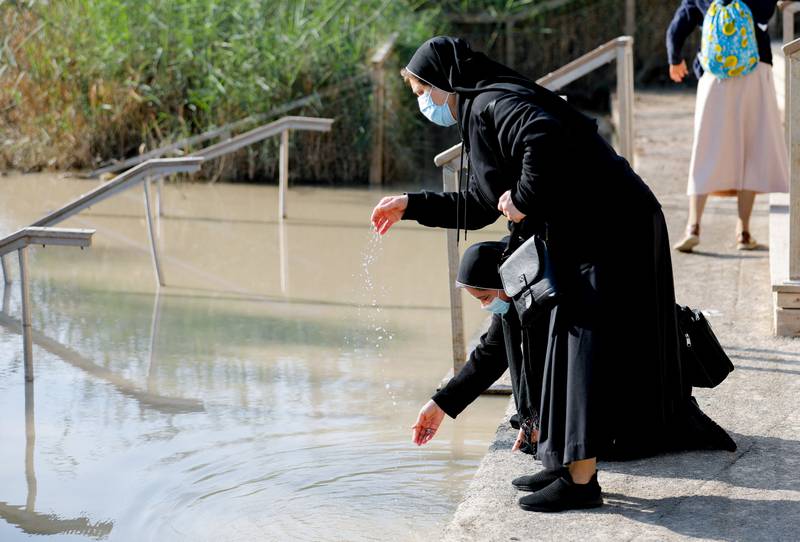 Nuns dip their hands in the waters of the Jordan River during a baptism near Jericho, in the Israeli-occupied West Bank.
