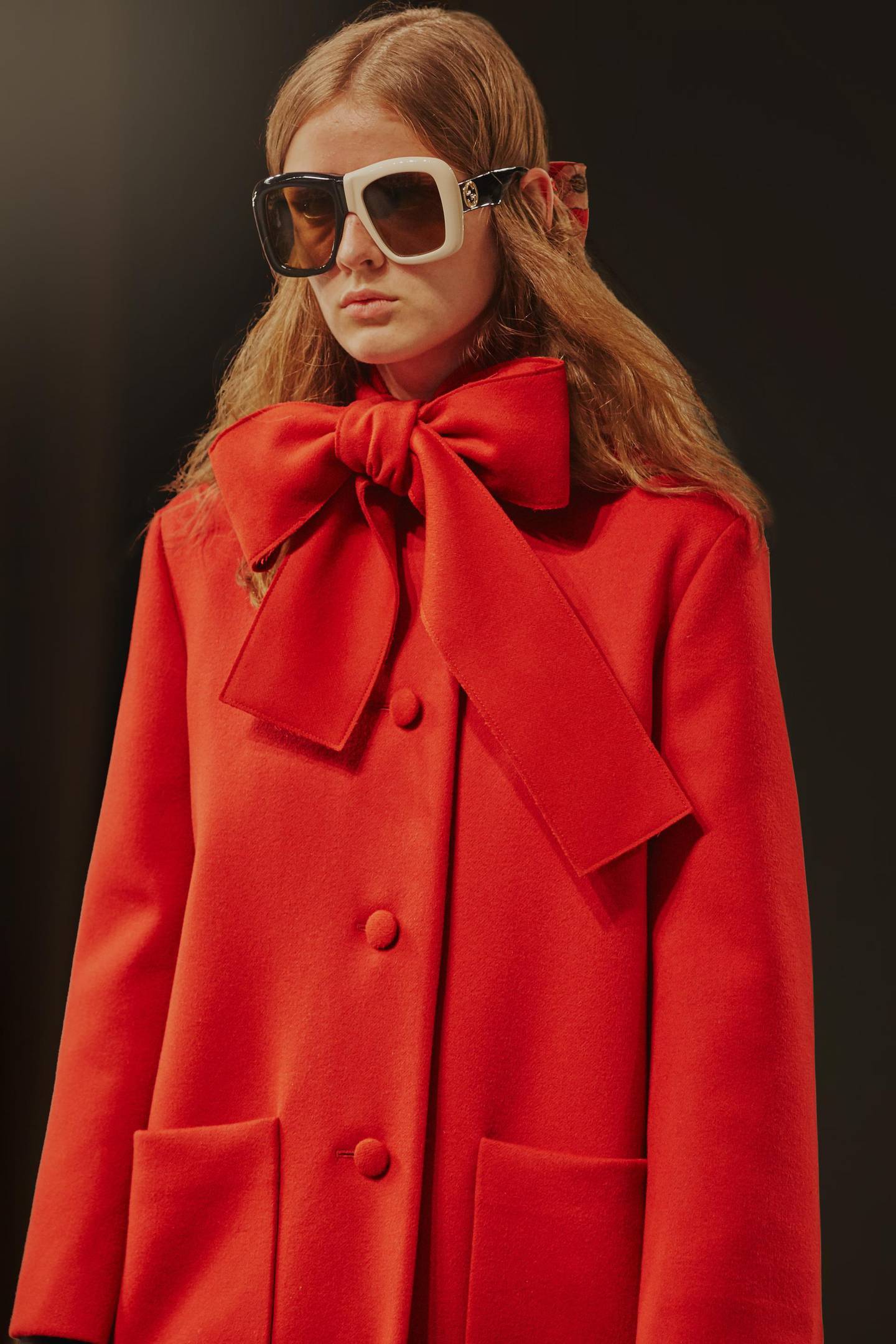 A heavy coat is given a playful bow at the neck, while mismatched sunglasses make this pure Gucci