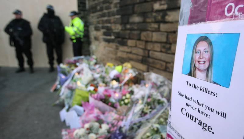 FILE PHOTO: A photograph of murdered police officer Sharon Beshenivsky is seen beside floral tributes as armed police guard the crime scene in central Bradford, November 19, 2005. Mother of three, Beshenivsky, 38, was shot dead and colleague Teresa Milburn, 37, was seriously injured by armed robbers when the two officers were called to a travel agency after an alarm was set off. REUTERS/ Russell Boyce -/File Photo