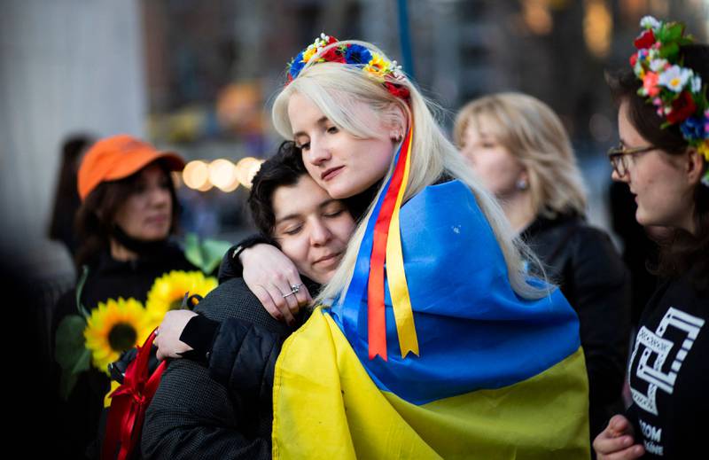 Women, wrapped in a Ukrainian flag, embrace during a flash mob protesting sexual abuse by Russian soldiers in Ukraine, at Washington Square Park in New York. AFP