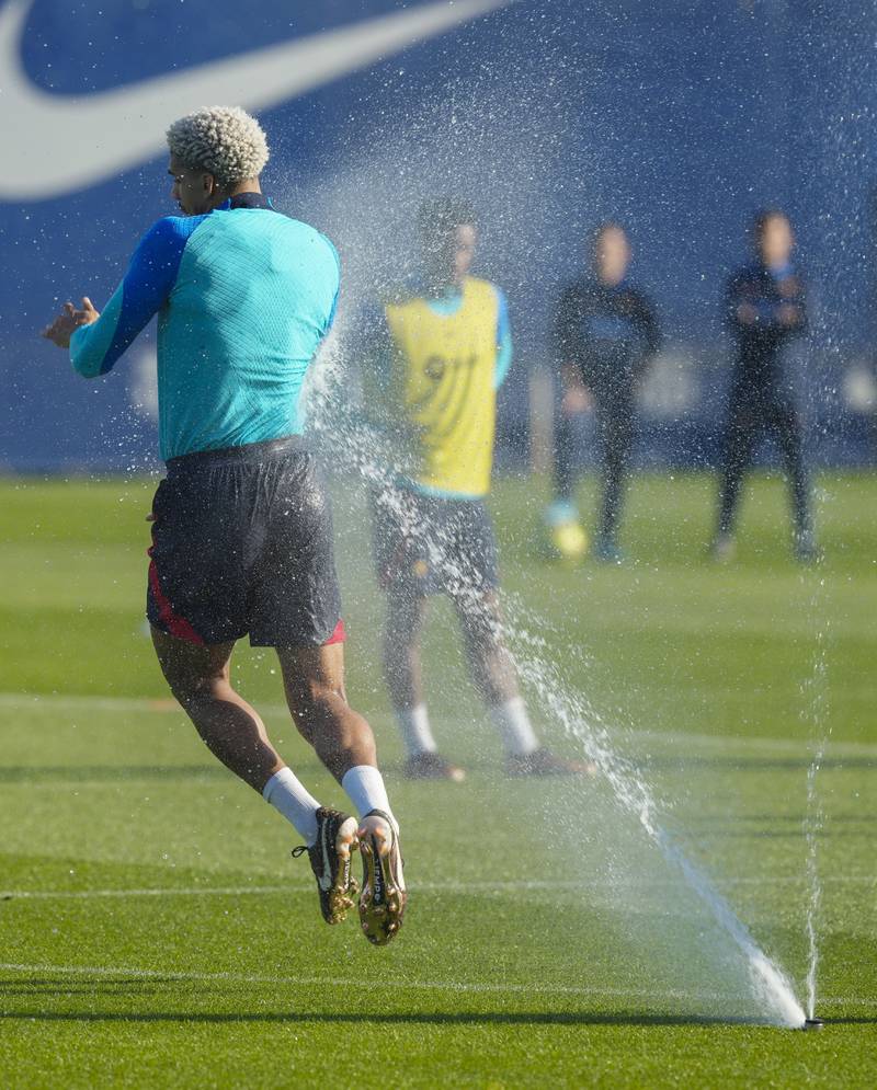 Barcelona's Ronald Araujo evades a sprinkler during training. EPA