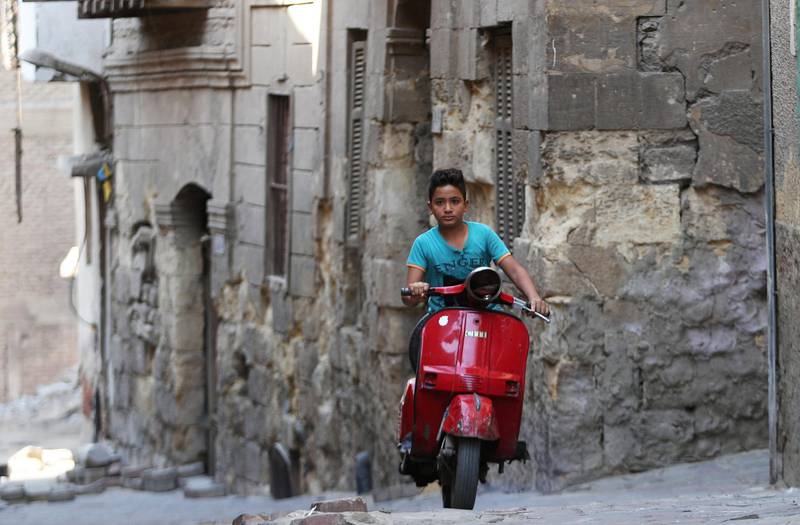 A boy rides a motorcycle past an old house at an alleyway in Darb al-Labbana hillside neighbourhood in Cairo, Egypt.  Reuters