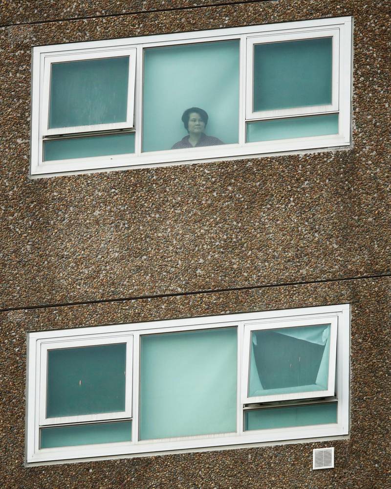 A resident looks out of a window from a public housing tower in North Melbourne, Australia. Police are enforcing a lockdown at towers in Melbourne after Victoria recorded over 100 new coronavirus cases.  EPA