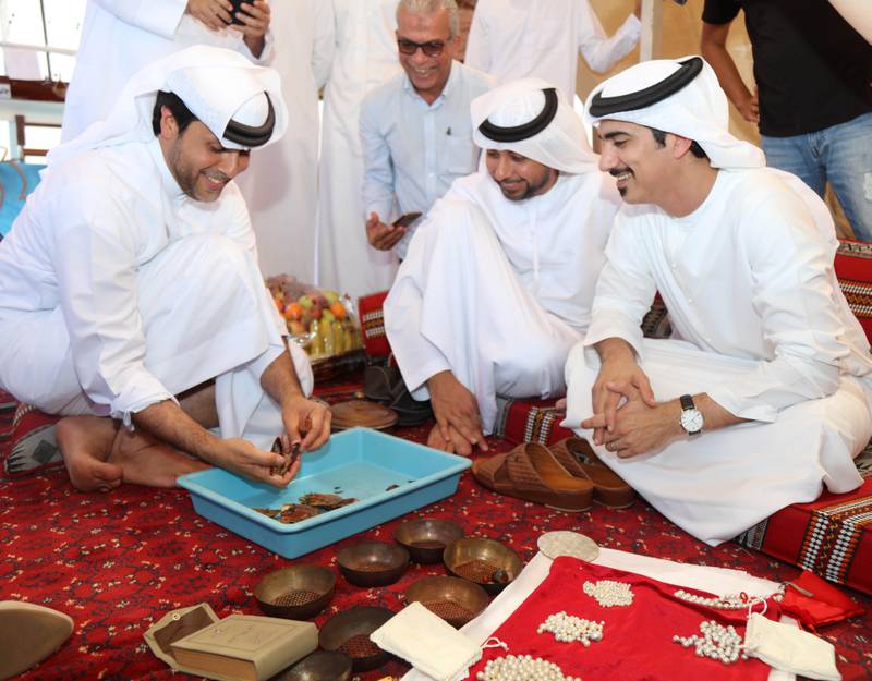 Sheikh Dr Majid Sultan Al Qasimi and Abdullah Al Suwaidi, founder of Suwaidi Pearls, watch oysters being opened. Courtesy Ministry of Climate Change and Environment
