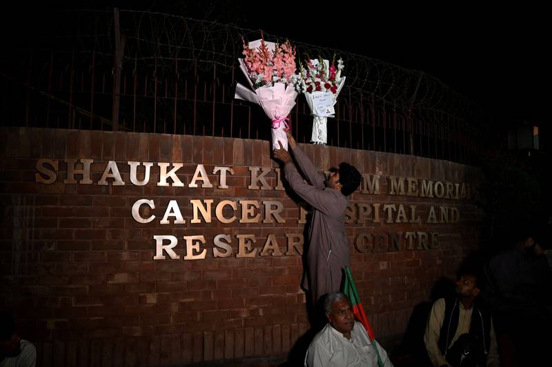A supporter of Mr Khan places flowers outside the hospital where he is being treated, in Lahore. AFP