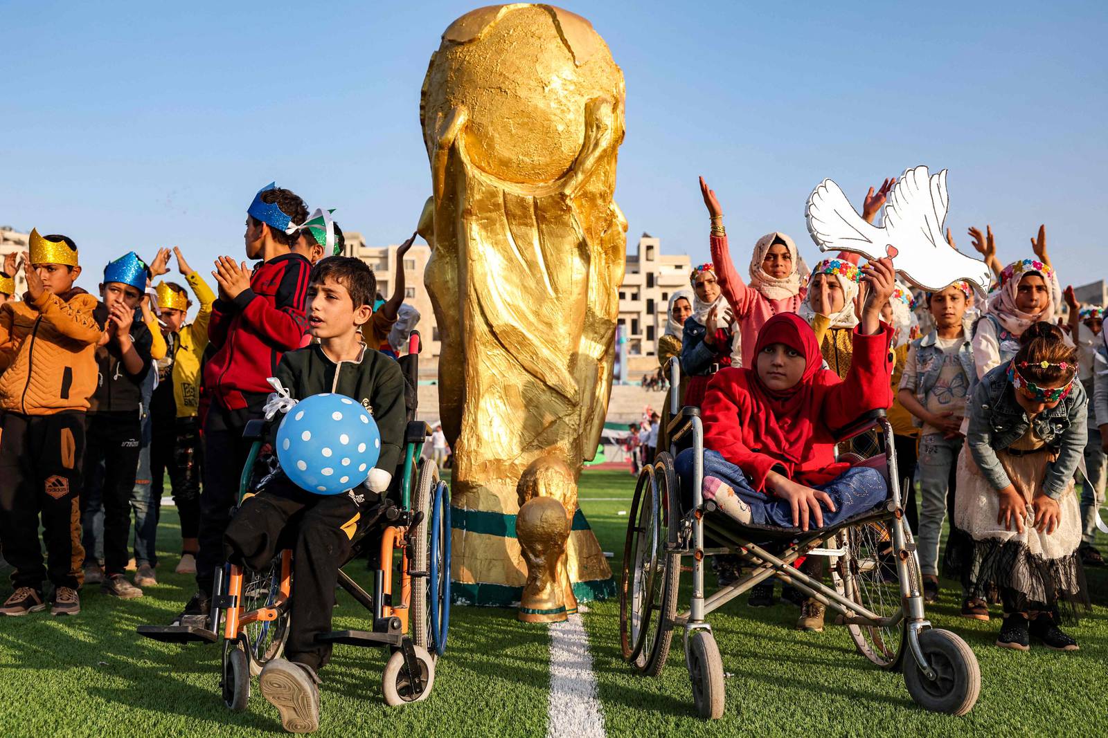 Des enfants posent devant une maquette du trophée de la Coupe du Monde de la FIFA.  Plus de 300 jeunes d'Idlib ont organisé leur propre Coupe du monde samedi, les organisateurs espérant mettre en lumière les communautés meurtries par 11 ans de guerre