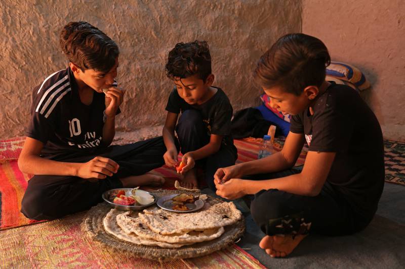 Brothers Khudair Abbas Elwan, 15, Haider Abbas Elwan, 7, and Hamza Abbas Elwan, 12, (L to R) eat together in their family home in Al-Bu Hussain. Their father, Abbas Elwan, took his own life in August after attempts to find water for his parched farmlands failed