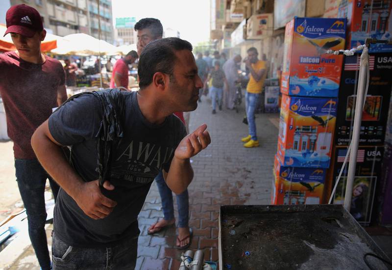 A Iraqi man uses a curbside shower to cool off during a heatwave. AFP