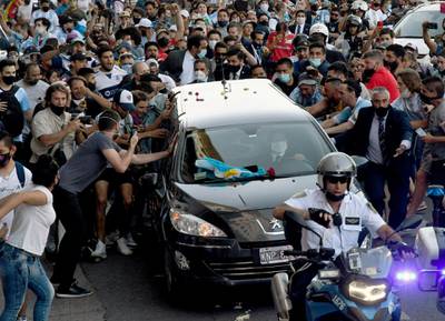 Fans next to the hearse carrying the late Argentine football legend Diego Maradona on its way from Casa Rosada presidential palace to the cemetery, in Buenos Aires. AFP