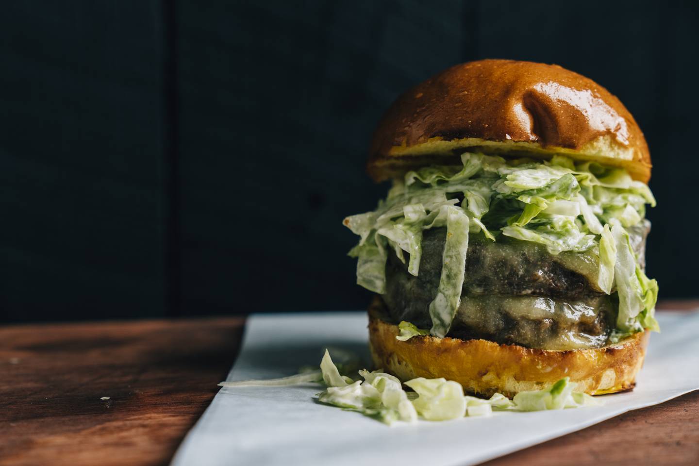 The DM Burger features a medium-rare patty topped with Vermont cheddar cheese, shaved onion and lettuce, and secret sauce on a brioche bun. Photo: Josh Telles