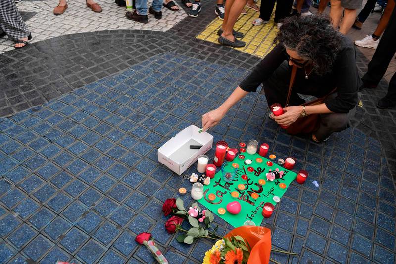 A woman lights a candle next to first flowers and a message to the victims on August 18, 2017 on the spot where yesterday a van ploughed into the crowd, killing 13 persons and injuring over 100 on the Rambla boulevard in Barcelona.
Drivers have ploughed on August 17, 2017 into pedestrians in two quick-succession, separate attacks in Barcelona and another popular Spanish seaside city, leaving 13 people dead and injuring more than 100 others. In the first incident, which was claimed by the Islamic State group, a white van sped into a street packed full of tourists in central Barcelona on Thursday afternoon, knocking people out of the way and killing 13 in a scene of chaos and horror. Some eight hours later in Cambrils, a city 120 kilometres south of Barcelona, an Audi A3 car rammed into pedestrians, injuring six civilians -- one of them critical -- and a police officer, authorities said. / AFP PHOTO / JAVIER SORIANO