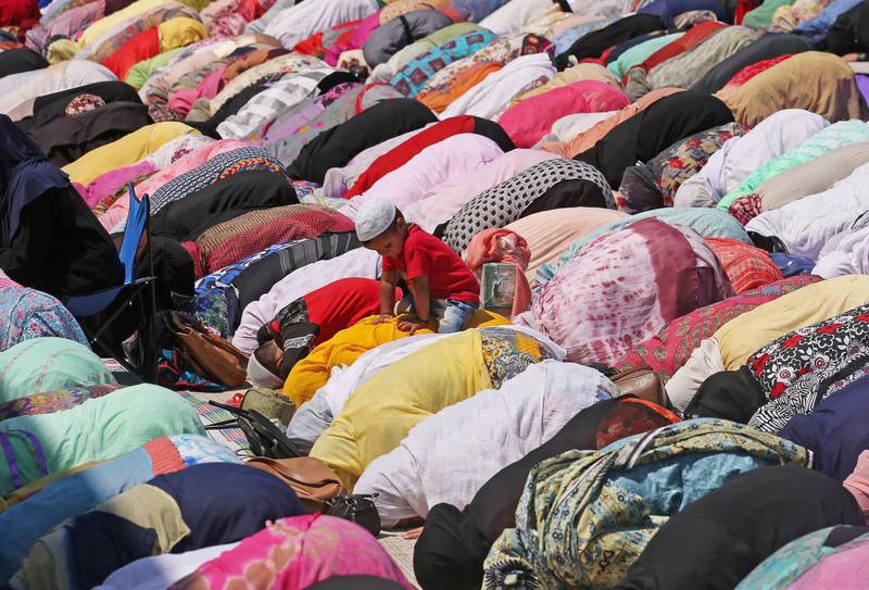 A boy sits on his mother's back as she and others pray during the death anniversary in Srinagar. Reuters