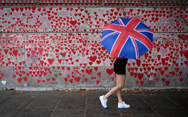 A pedestrian walks past the National Covid Memorial Wall in London, which sadly had many new additions this summer. EPA