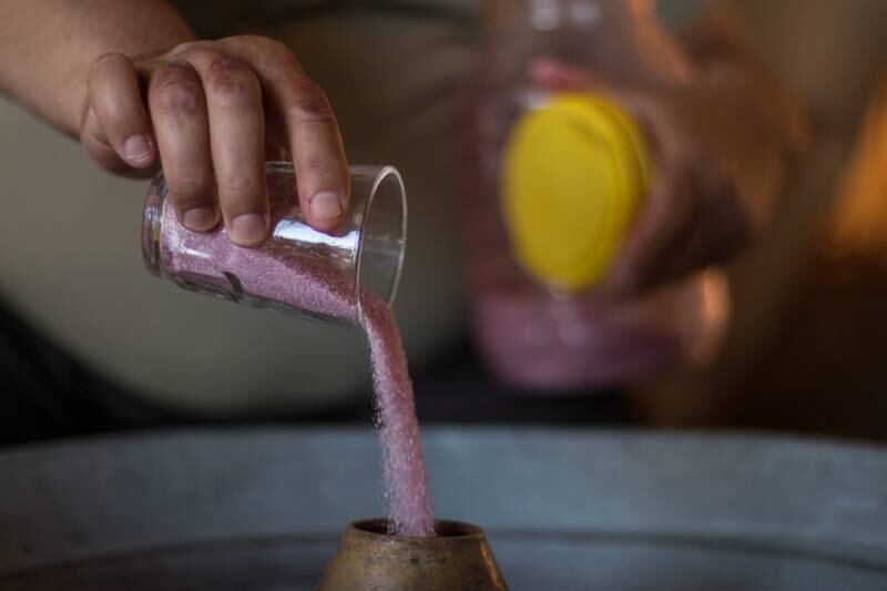 He mixes sugar and dye to make the ghazl al banat.