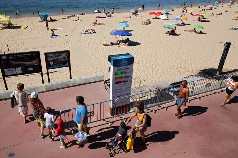 Beachgoers check a semaphore system that signals how crowded the beach is in Oeiras, outside Lisbon, on July 15. The system uses radar to count people entering the gates to the fenced beach to help sunbathers maintain social distance. AP Photo