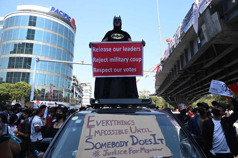 A protester dressed in a batman outfit holds a sign as they take part in a demonstration against the military coup in Yangon on February 10, 2021. / AFP / Sai Aung Main
