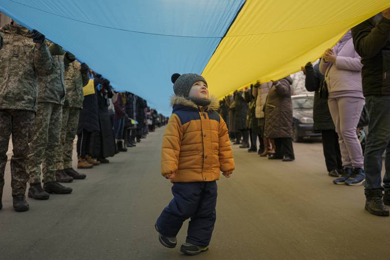 A child walks under a large Ukrainian flag carried by people in Sievierodonetsk, the Luhansk region, eastern Ukraine. AP Photo