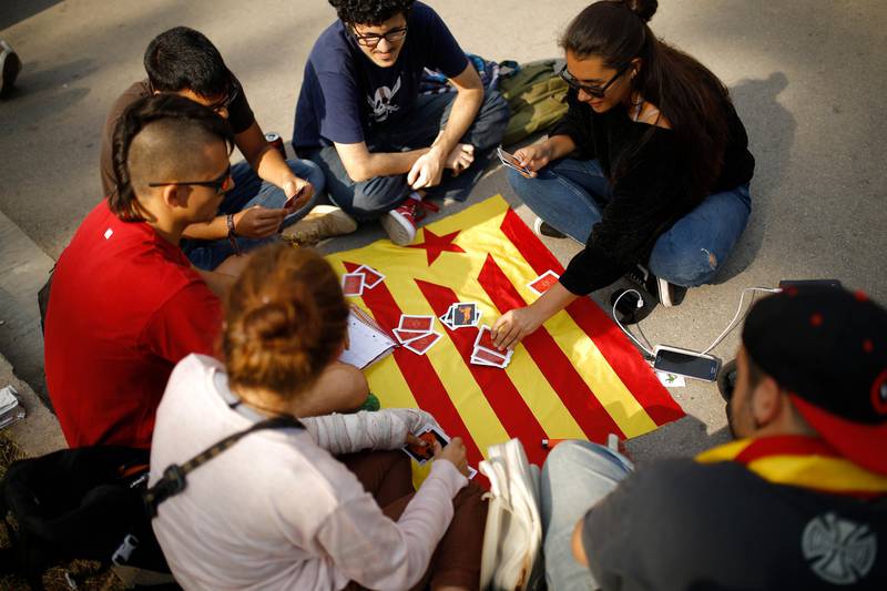 Young people play cards on a Catalan flag in Barcelona, Spain, Tuesday, Oct. 10, 2017. Catalonia's regional leader was addressing parliament Tuesday in a highly anticipated session that could spell the birth of a new republic, marking a critical point in a decade-long standoff between Catalan separatists and Spain's central authorities. (AP Photo/Francisco Seco)