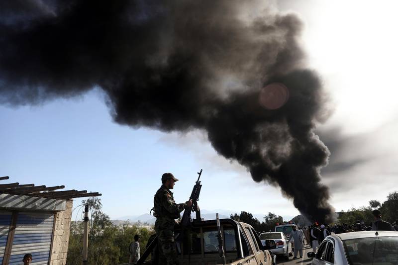 An Afghan army soldier stand guard as smoke rises from a burning fuel tanker on the Jalalabad-Kabul highway, east of Kabul, Afghanistan, Wednesday, April 21, 2021. (AP Photo/Rahmat Gul)