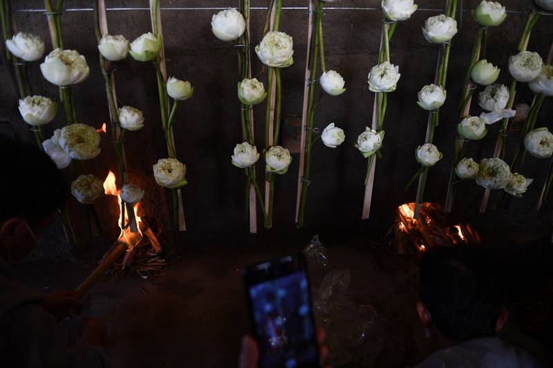 A Buddhist monk takes photos of lotus flowers by the cremator. AFP