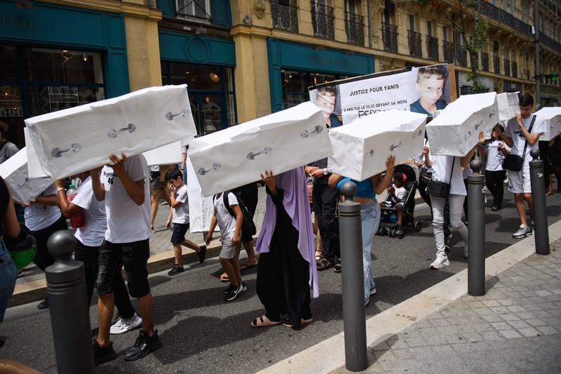 Protesters carry cardboard replicas of coffins during a march to pay tribute to victims of killings that remain unsolved or unpunished, in Marseille on June 15, 2022. AFP