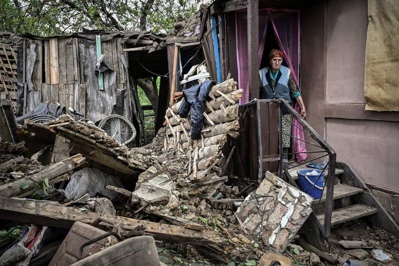 An elderly woman stands inside her heavily damaged house after it was hit by a missile in Bakhmut. AFP