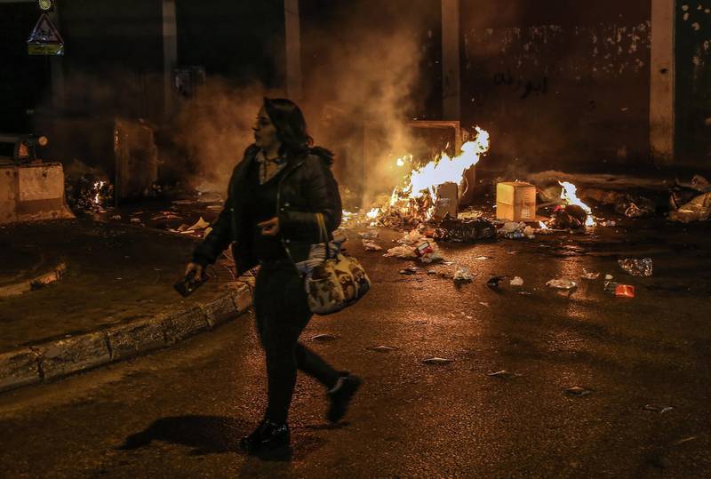 A woman passes by burning waste where supporters of Outgoing Prime Minister Saad Hariri closed the road during a protest against the newly appointed Lebanese Prime Minister Hassan Diab, at  Al-Barbir neighborhood in Beirut.  EPA