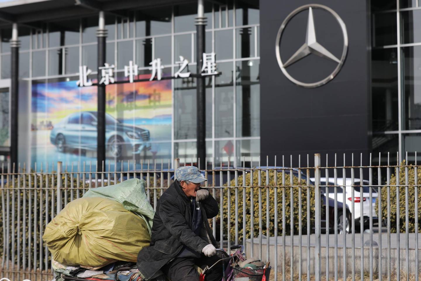 epaselect epa06414044 A Chinese man rides a tricycle past a Mercedes-Benz auto dealership building in Beijing, China, 03 January 2018. China stopped the production of 553 vehicle models that have not met the government's fuel consumption standards to curb pollution. The policy, which started 01 January 2018, affects vehicles models from such brands as Mercedes-Benz, BMW, Audi, Volkswagen and others.  EPA/WU HONG