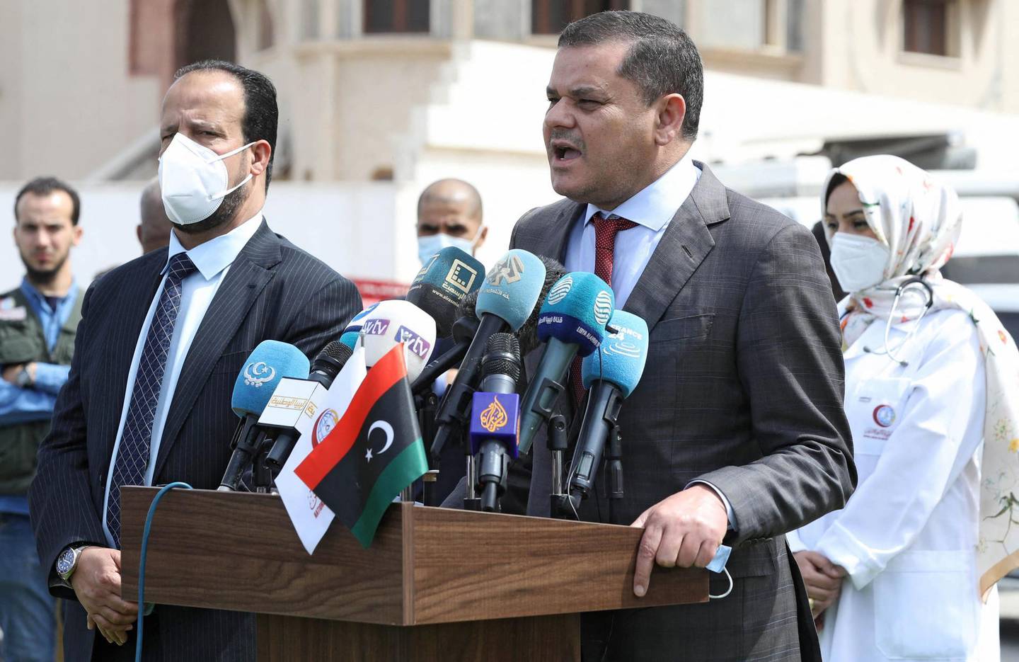 Libyan Prime Minister Abdelhamid Dbeibah, is joined by Health Minister Ali al-Zenati (L), as he delivers a speech outside the Centre for Disease Control in the capital Tripoli on April 10, 2021, at the launch of the national vaccination campaign. Libya officially launched its coronavirus vaccination campaign, starting with the Prime Minister, health authorities in the conflict-wracked nation said. Dbeibah urged fellow citizens to register online for their own vaccinations.
 / AFP / Mahmud TURKIA
