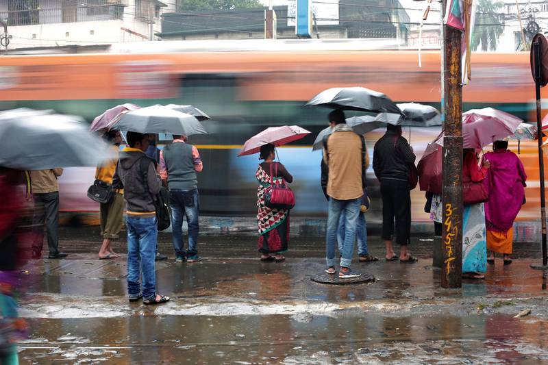 Indian commuters protect themselves with umbrellas as they wait on street during a continuous rain shower in Kolkata, India. EPA