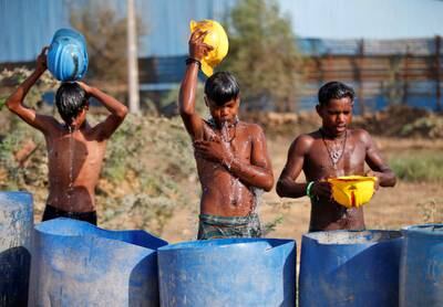 Youths use their helmets to pour water over themselves near a construction site on the outskirts of Ahmedabad. Reuters