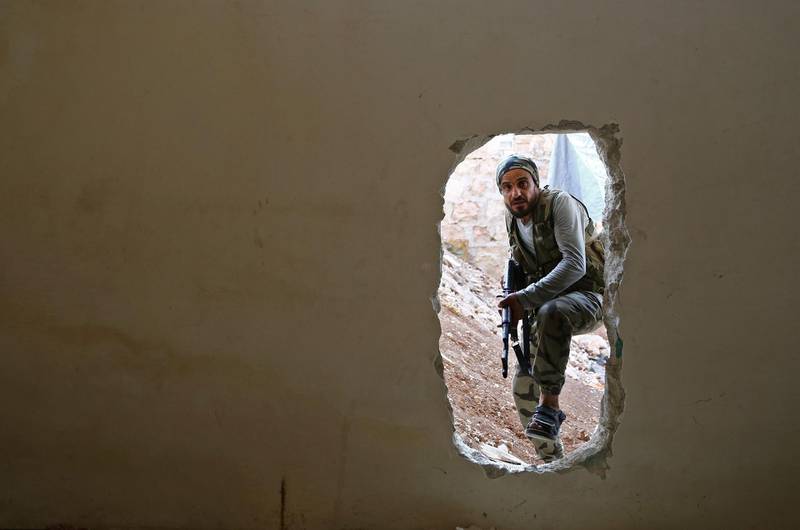 A Turkish-backed Syrian fighter crosses into a building through a hole in the wall in Tadef, in the eastern countryside of Aleppo. AFP