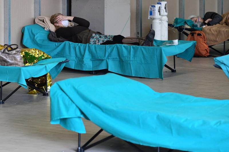 Patients lie in bed at a temporary emergency structure set up outside the accident and emergency department, where any new arrivals presenting suspect new coronavirus symptoms will be tested, at the Brescia hospital, Lombardy, on March 13, 2020. / AFP / Miguel MEDINA
