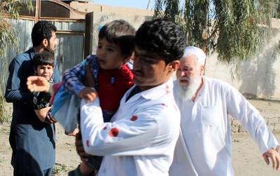 Men carry children away from an explosion site in Lashkar Gah, capital of southern Helmand province, Afghanistan, Saturday, Feb. 24, 2018. In a second suicide bombing attack near another military base in Helmand's capital city Lashkar Gah, one security person was killed and seven civilians wounded, Omar Zwak, spokesman for the provincial governor in Helmand said. (AP Photo)