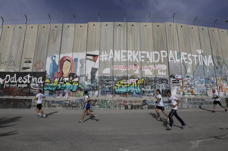 Participants run past Israel's West Bank separation barrier during the Palestine Marathon in Bethlehem. Ammar Awad / Reuters


