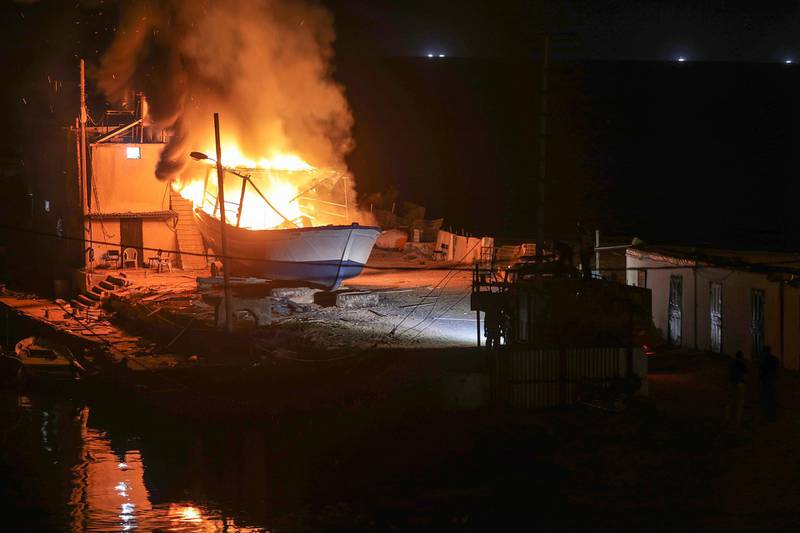 epa06756689 Palestinian firefighters inspect a burning fishing boat after an alleged Israeli airstrike in in west Gaza City, 23 May 2018.  EPA/MOHAMMED SABER