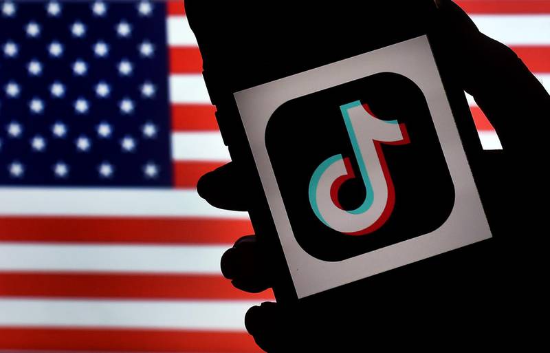 (FILES) In this file illustration photo taken on August 3, 2020  the social media application logo TikTok is displayed on the screen of an iPhone on an American flag background in Arlington, Virginia.  The US is expanding its China-targeted Clean Network program to include Chinese-made cellphone apps and cloud computing services that it claims are security risks, Secretary of State Mike Pompeo announced on August 5, 2020. / AFP / Olivier DOULIERY
